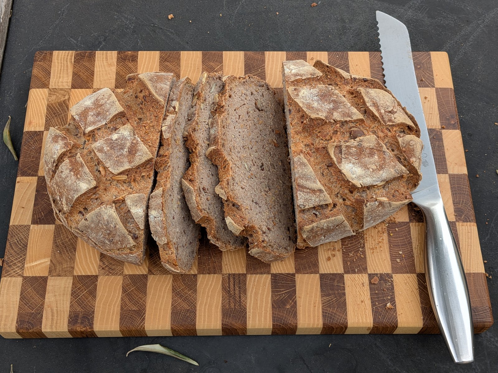 Seconde planche en damier avec un pain partiellement tranché et un couteau à pain dentelé sur le côté droit.